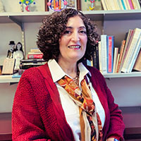 A college professor in her office wearing a red sweater